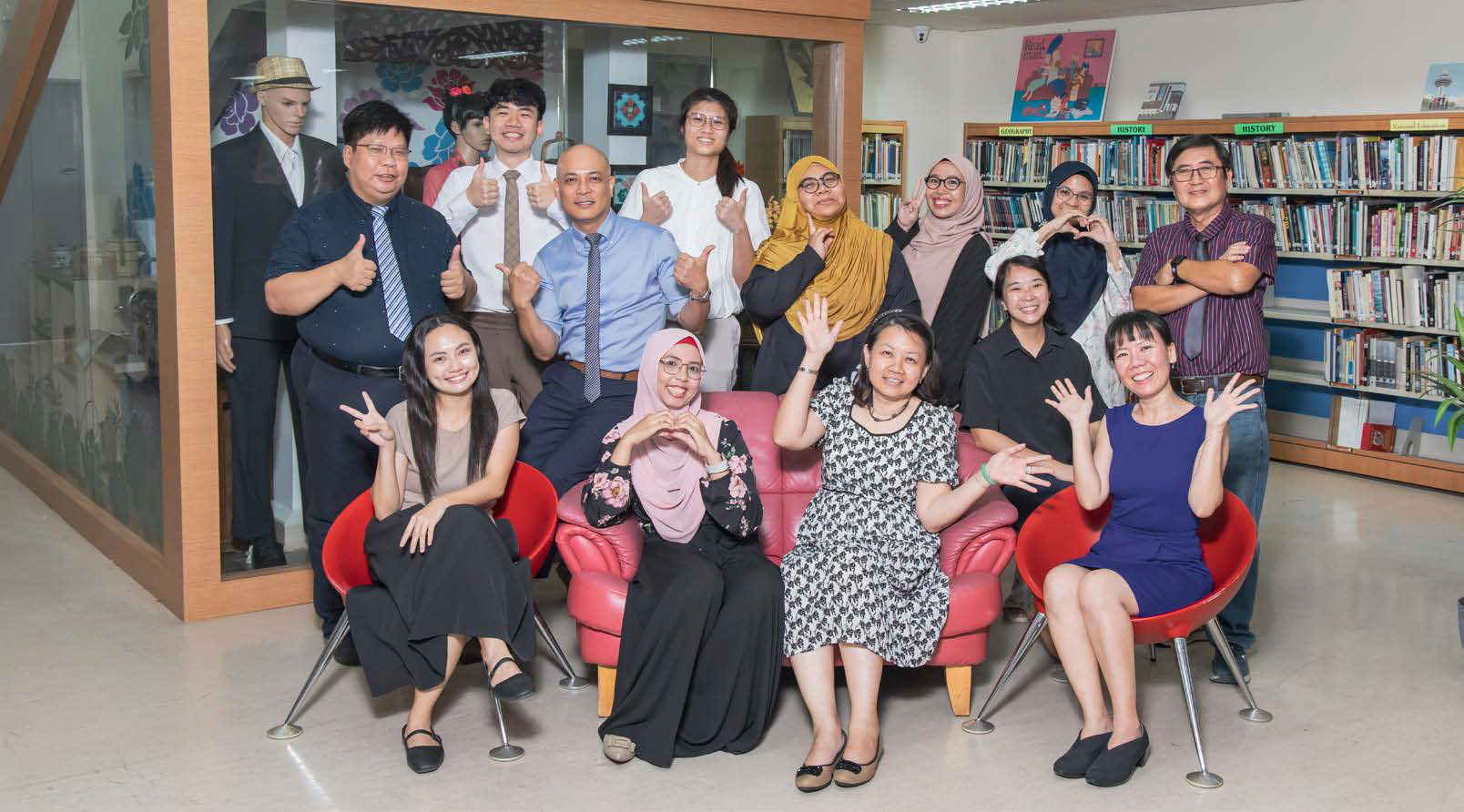 Thirteen educators pose on a a shared sofa for a photo